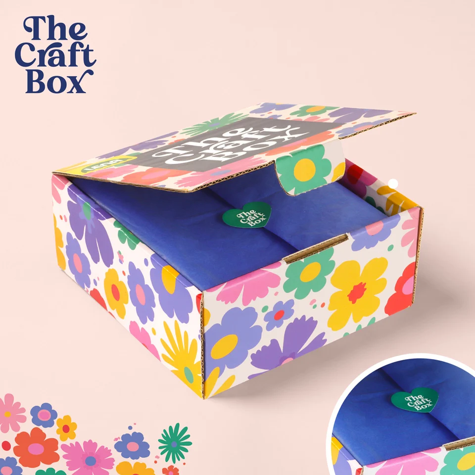 Geöffnete Schachtel mit buntem Blumenmuster und blauem Seidenpapier im Inneren