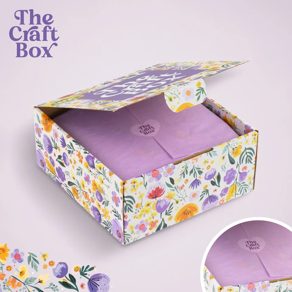 Offene Schachtel mit Blumenmuster und violettem Papier im Inneren